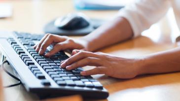 A pair of hands typing on a computer keyboard